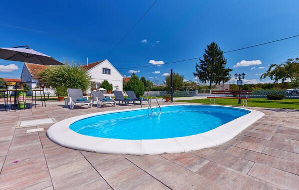 A swimming pool with lounge chairs and a barbecue area.