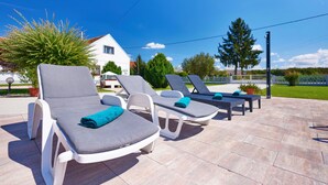 A patio with lounge chairs and a white house in the background. - Stunning home in Gudovac (Gudovac)