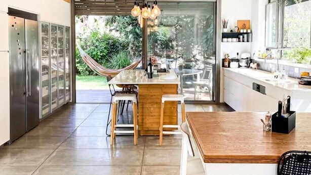 Una cocina moderna con una isla grande, electrodomésticos de acero inoxidable y una lámpara colgante.