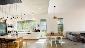 Una cocina moderna con una isla central, armarios blancos y un comedor con mesa y sillas de madera.