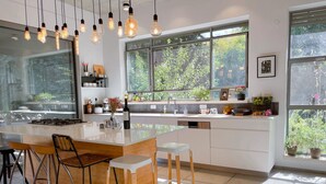 Una cocina moderna con una isla central, taburetes de bar e iluminación colgante.