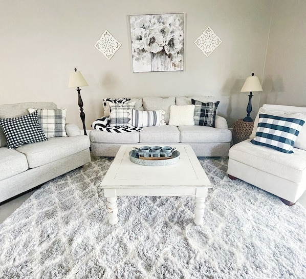 Un salon avec un canapé gris, une table basse blanche et un tapis à motifs.