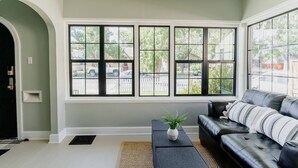 A living room with a large window, a black leather sofa, and a small table with a plant.