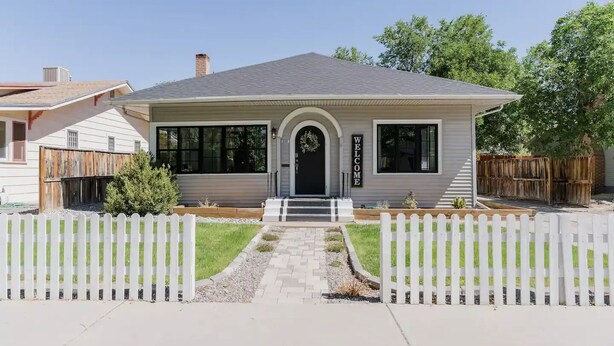 A single-story house with a front porch, a welcome sign, and a picket fence.