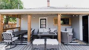 An outdoor patio with a dining table and chairs, a cushioned bench, and string lights.