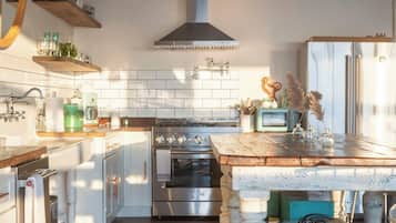 A kitchen with a central island, stainless steel appliances, pendant lighting, and a rustic wooden floor.