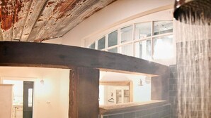 A bathroom with a shower, a wooden floor, and a view into the adjacent room. - Sleep in a barn while enjoying the luxury accommodations  and friendly farm animals on property! (Perry)