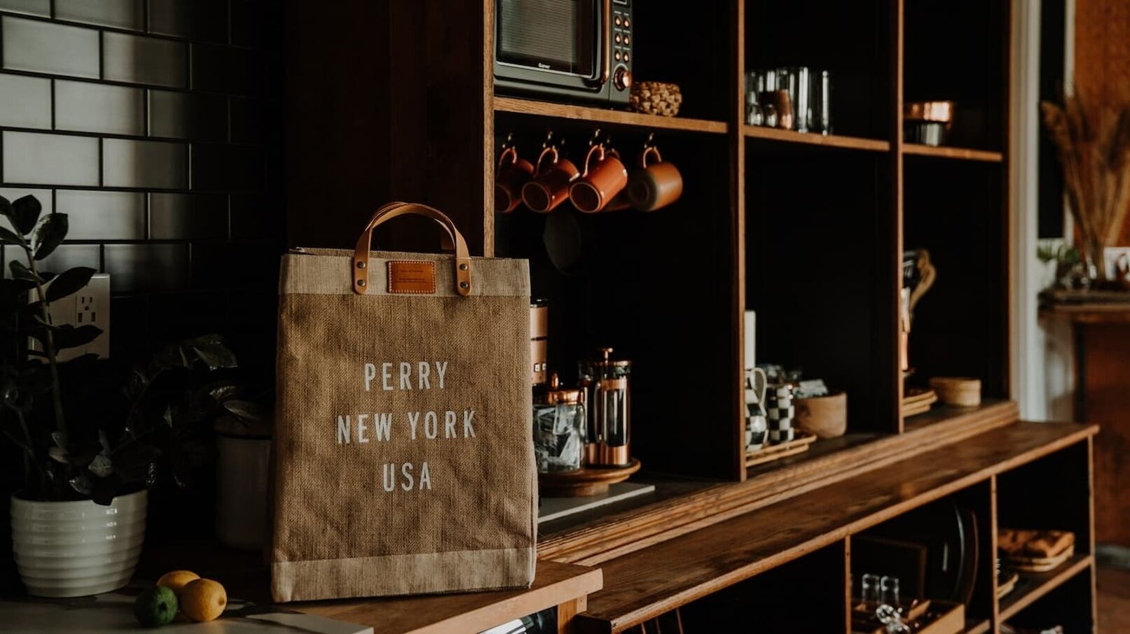 Et køkken med en træbordplade, en ophængt grydestativ og en stor brun papirspose med teksten "PERRY NEW YORK USA".