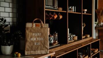 Et køkken med en træbordplade, en ophængt grydestativ og en stor brun papirspose med teksten "PERRY NEW YORK USA".