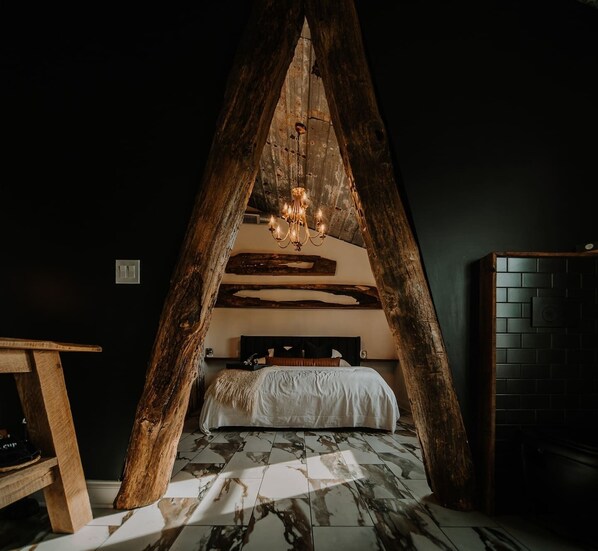 A cozy bedroom with a sloped ceiling, a wooden headboard, a bed with a white bedspread, and a chandelier. - Southview @ the West Barn - Great Letchworth View! (Perry)