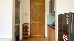 A compact kitchen with a wooden door, a refrigerator, and a sink.