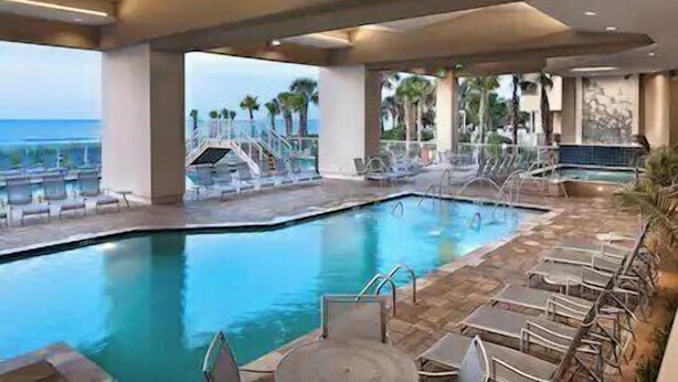 Un espace piscine avec des chaises longues, un jacuzzi et une vue sur l’océan.