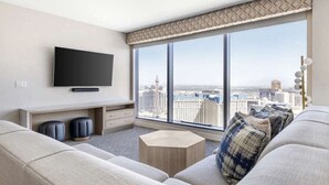 A modern living room with a large window, a flat-screen TV, a sofa, a coffee table, and a small side table. - Las Vegas | Pool & Strip Access | Contemporary Vegas Stay (Las Vegas)
