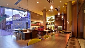 A modern restaurant with a long wooden table, bar stools, and hanging pendant lights. - Las Vegas | Pool & Strip Access | Contemporary Vegas Stay (Las Vegas)