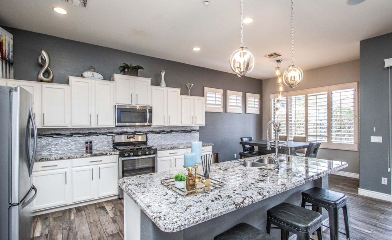 A modern kitchen with white cabinets, granite countertops, and a large island with bar stools.