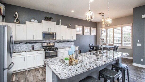 A modern kitchen with white cabinets, granite countertops, and a large island with bar stools.