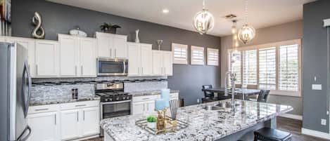 A modern kitchen with white cabinets, granite countertops, and a large island with bar stools.