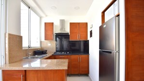 Eine moderne Küche mit Holzausziehtüren, einem Edelstahlkühlschrank und einem schwarzen Herd.