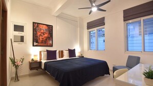 Ein Schlafzimmer mit einem Bett, Nachttischen, einem Deckenventilator, einem Fenster und einem Sessel.