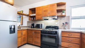 A kitchen with wooden cabinets, a stainless steel refrigerator, a stove, and a microwave.