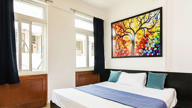A bedroom with a large bed, a window with curtains, and a colorful painting on the wall. - Spacious 2 Bedroom Apt @Prime-Location, Colonial Zone (OldTown) (Santo Domingo)