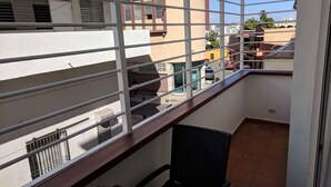 Un balcón con vistas a edificios cercanos y un coche estacionado.