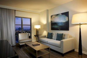 A modern hotel room with a sofa, armchair, and a coffee table. A large window offers a city view. - Orlando | Lakeside Escape | Resort Pool & Theme Parks Nearby (Orlando)