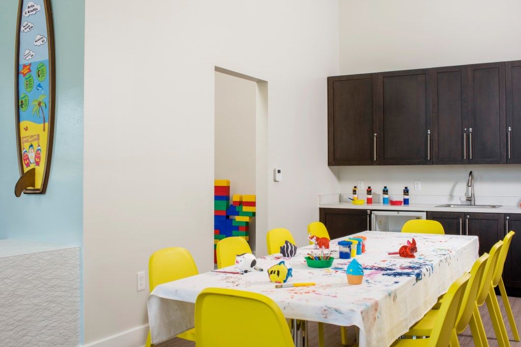 A dining area with a table set for four, yellow chairs, and a white tablecloth.