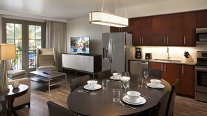 A modern kitchen with dark wood cabinets, stainless steel appliances, and a dining area with a round table set for four. - Las Palmeras, a Hilton Grand Vacations Club - 2 Bedroom Lock Off - 2LK (Orlando)