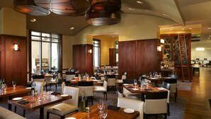 A spacious restaurant with multiple dining tables and chairs, wooden paneling, and a modern chandelier. - Las Palmeras, a Hilton Grand Vacations Club - 2 Bedroom Lock Off - 2LK (Orlando)