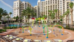 A hotel pool area with water play features, lounge chairs, and palm trees. - Las Palmeras, a Hilton Grand Vacations Club - 2 Bedroom Lock Off - 2LK (Orlando)
