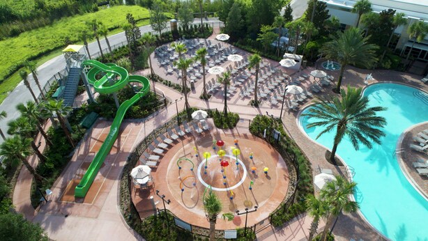An aerial view of a resort with a water park, a swimming pool, and a landscaped area with lounge chairs and umbrellas. - Las Palmeras, a Hilton Grand Vacations Club - 2 Bedroom Lock Off - 2LK (Orlando)
