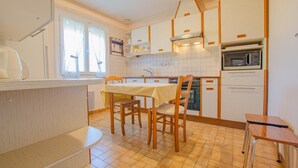 Cocina compacta con mesa, sillas, microondas y estufa.