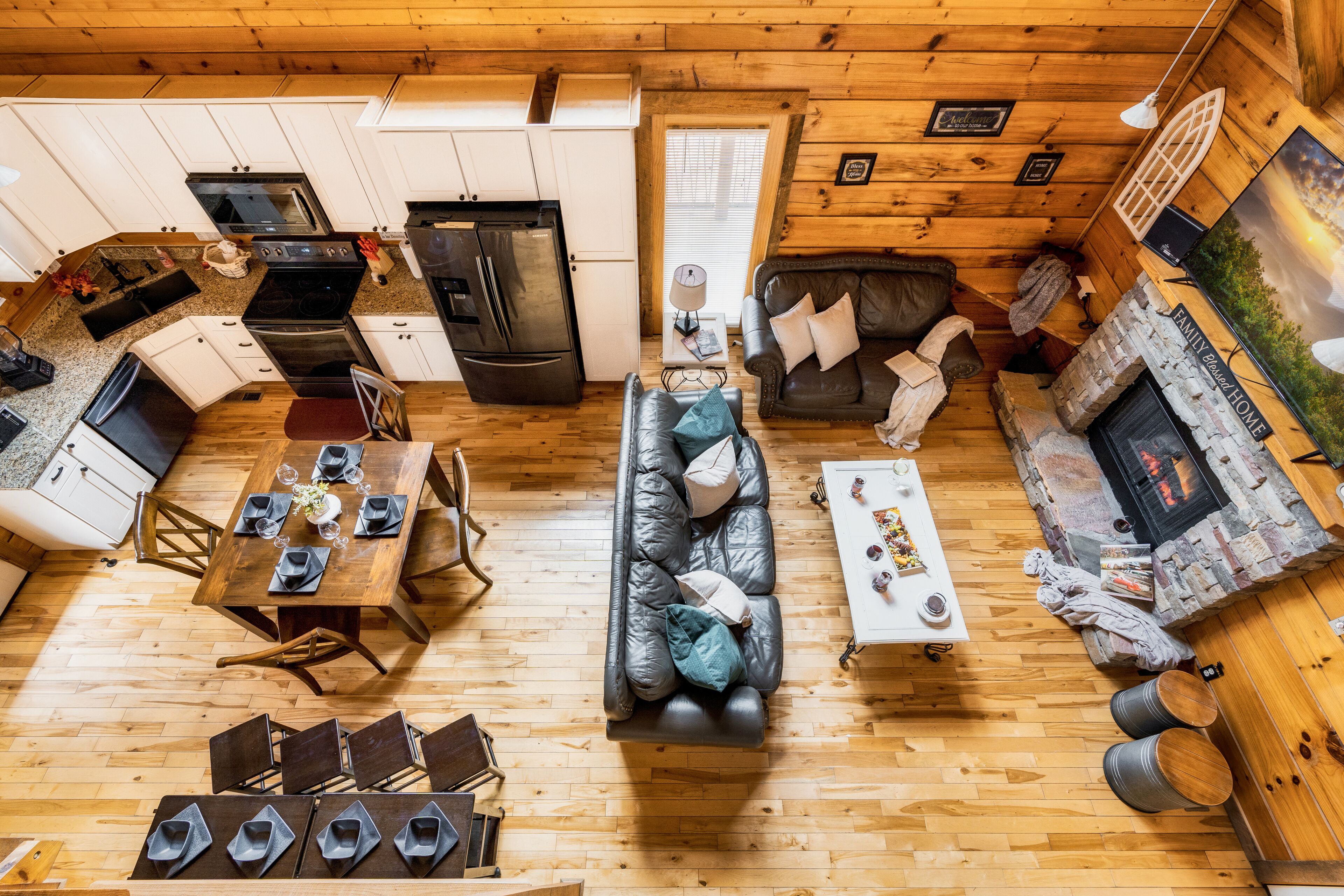 Un interior de cabaña con comedor, sofá, chimenea y cocina.