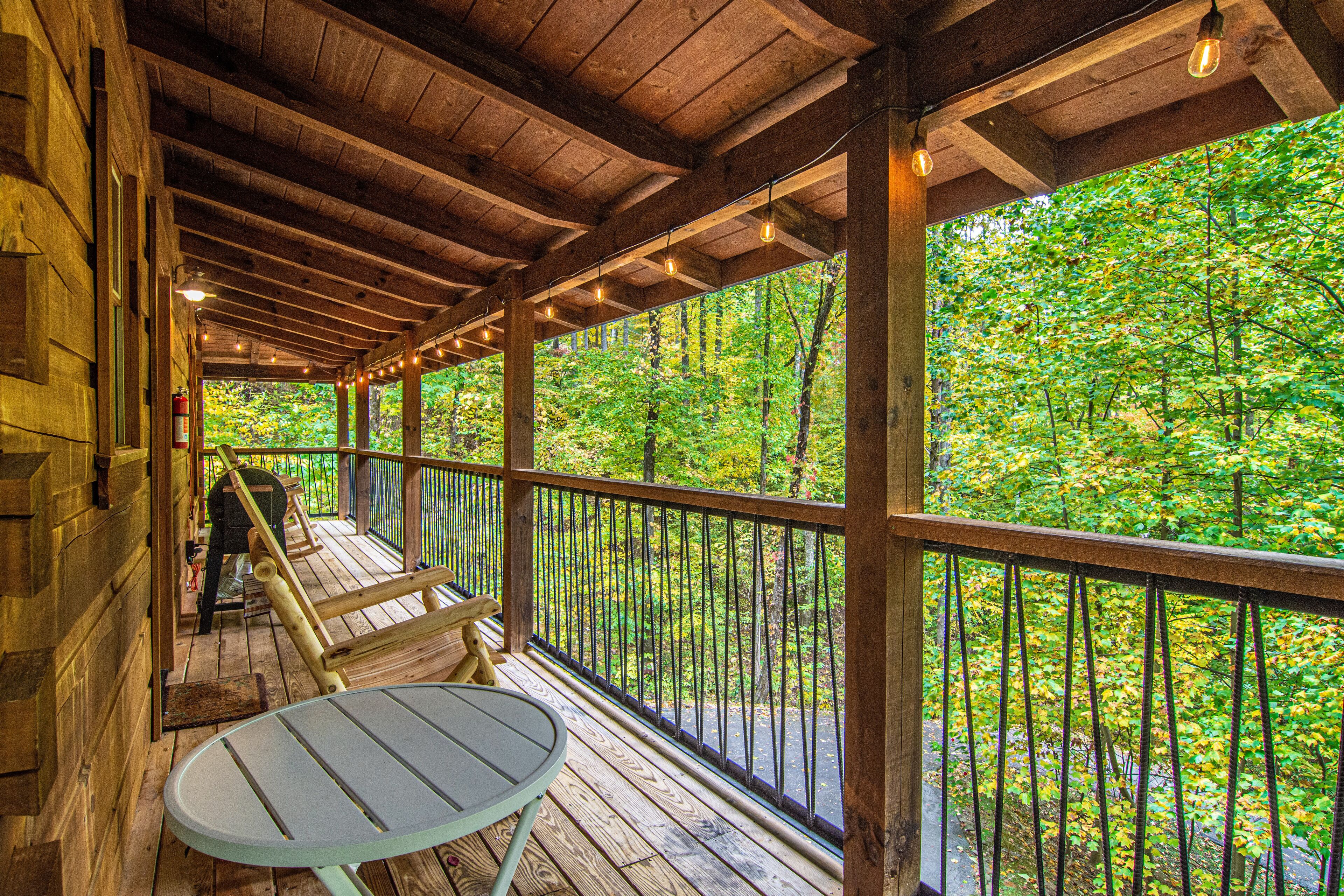 A wooden deck with a table and benches overlooking a forest.