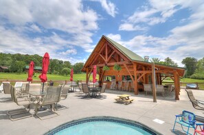 A wooden gazebo with a pool table and chairs, surrounded by red umbrellas, set against a backdrop of a clear sky and greenery. - Hot tub /Theater Room 📽 X-Box 🕹 Pool Table / 5% Military/Senior Discount (Sevierville)