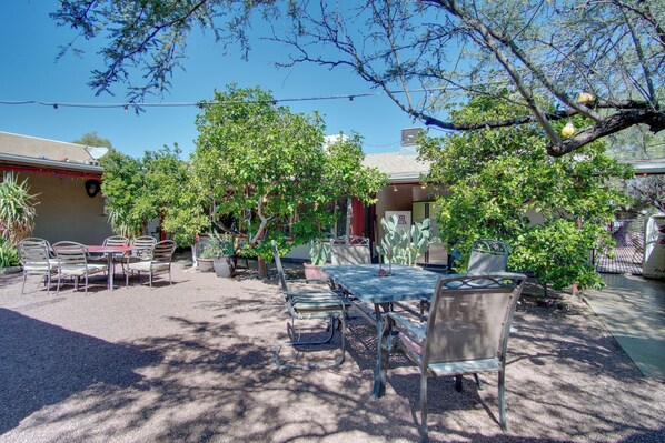 Eine Außenpatio-Terrasse mit Tisch und Stühlen, umgeben von Bäumen und Pflanzen.