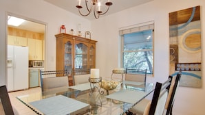 A dining area with a glass table, cushioned chairs, a wooden cabinet with glass doors, and a window with blinds. - 5 Mi to Dtwn: Tuscon Escape w/ Yard & Patio! (Tucson)