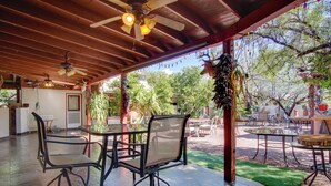 An outdoor patio with tables and chairs, a ceiling fan, and a view of the surrounding trees. - 5 Mi to Dtwn: Tuscon Escape w/ Yard & Patio! (Tucson)