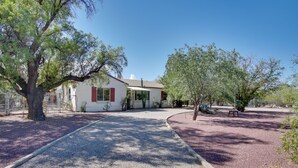 A house with a gravel driveway, a tree in the foreground, and a clear blue sky. - 5 Mi to Dtwn: Tuscon Escape w/ Yard & Patio! (Tucson)