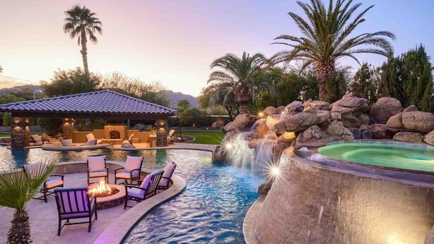 A pool area with a hot tub, lounge chairs, and a stone structure with a fireplace. - 7BR Luxury Oasis w/ Relaxing Lazy River, Basketball, Full Gym & Private Theater (Paradise Valley)