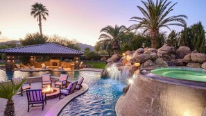 A pool area with a hot tub, lounge chairs, and a stone structure with a fireplace. - 7BR Luxury Oasis w/ Relaxing Lazy River, Basketball, Full Gym & Private Theater (Paradise Valley)
