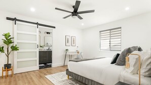 Een moderne slaapkamer met een bed, nachtkastje en plafondventilator.