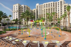 A hotel courtyard with a pool, lounge chairs, and a water play area. - Orlando | Poolside Escape | Resort Pool & Theme Parks Nearby (Orlando)