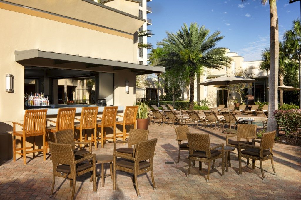 Eine Terrasse im Freien mit Korbmöbeln, einer Bar und Palmen.