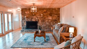 Una sala de estar acogedora con chimenea de piedra, suelo de madera y un sofá cómodo.