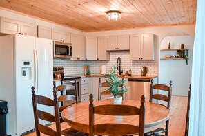 A kitchen with white cabinets, a wooden dining table, and chairs. - New! River Retreat! Spacious home on the Little Pigeon River! (Sevierville)