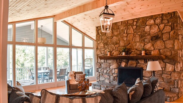 Una sala de estar acogedora con chimenea de piedra, ventanas amplias y un espacio de descanso cómodo.