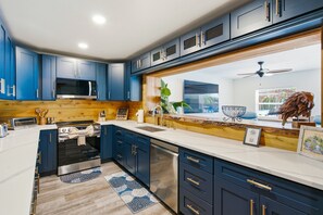 A modern kitchen with blue cabinets, stainless steel appliances, and a wooden backsplash. - Waterfront 5-bed 4 bath with heated pool BTR 2030 (Indian Rocks Beach)