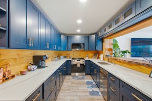 Una cocina moderna con gabinetes azul oscuro, electrodomésticos de acero inoxidable y una pared de acento de madera.